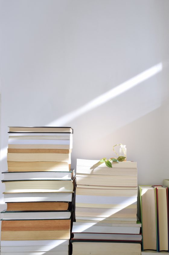 Pile of books stacked against a white wall